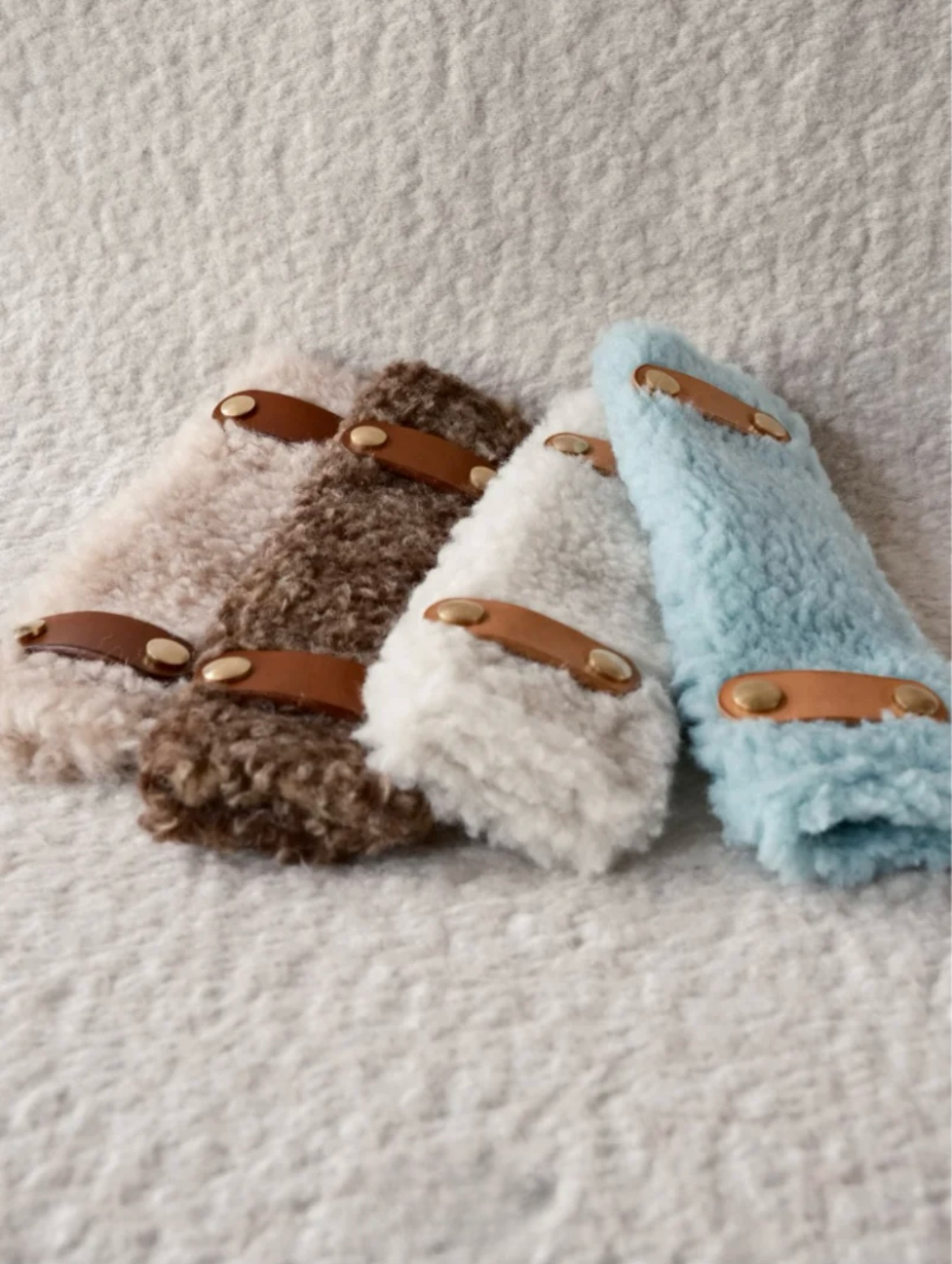 Soft-shell fluffy pads in brown, white, and blue paired with detachable designer leather collars for dogs, made from fluffy Merino wool.